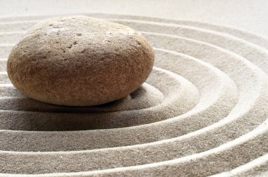 Zen bahçesi meditasyon taşı arka planında rahatlama dengesi ve ahenk ruhsallığı veya spa sağlığı için kumdaki taşlar ve çizgiler var.