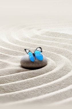 Zen bahçesi meditasyon taşı arka plan ve rahatlama dengesi ve ahenk ruhsallığı veya spa sağlığı için kumdaki taşlar ve çizgilerle kelebek..