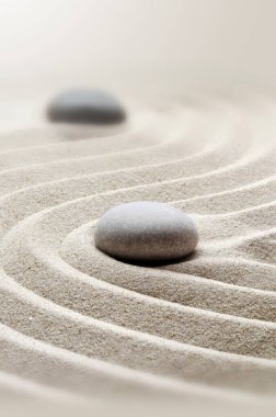 Zen bahçesi meditasyon taşı arka planında rahatlama dengesi ve ahenk ruhsallığı veya spa sağlığı için kumdaki taşlar ve çizgiler var..