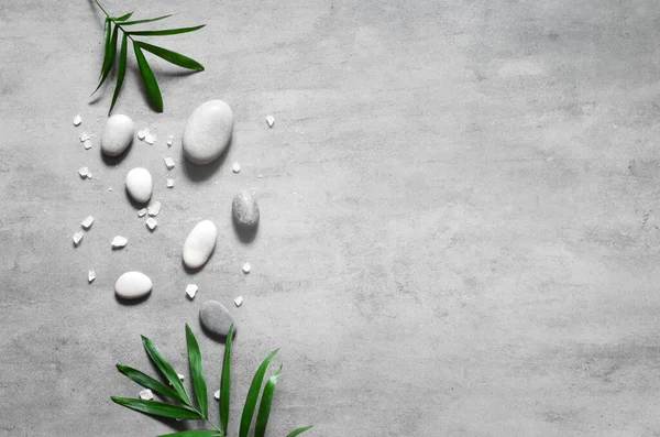 Grey spa background, spa concept, palm leaves and grey stones, top view