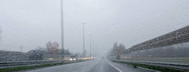   Autobahn yağmurlu havalarda. Fotoğraf yağmurlu havalarda arabanın camdan bir yol gösterir. Bulanık ses ekranları ve farlar karşıdan gelen araçların gösterir.             