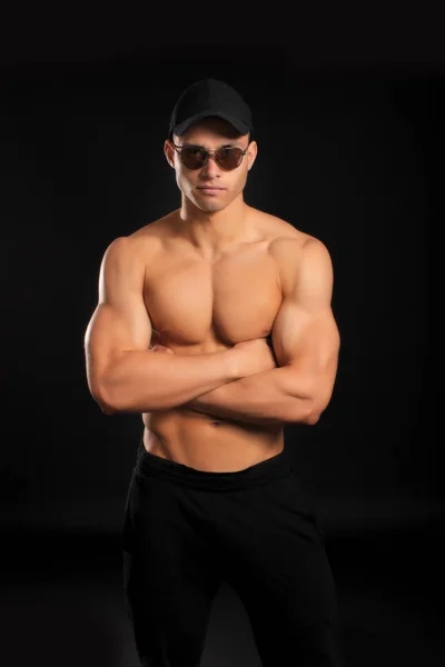 Guapo culturista hombre con un torso desnudo mostrando los músculos en la tapa y las gafas — Foto de Stock