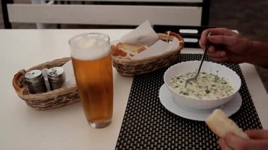 man eats cold soup at white table