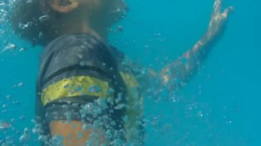 Boy in T-shirt tries to swim out of the pool