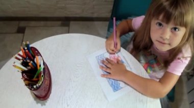 girl with a pencil in her hand raises her head up and looks at the camera