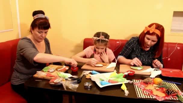 年轻妇女和一个女孩在餐桌旁装饰姜饼饼干 — 图库视频影像
