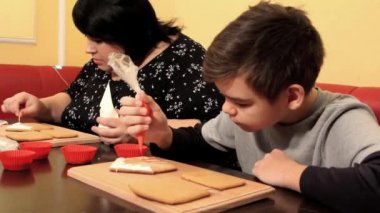 Çocuklu şişman bir kadın zencefilli ekmek süslüyor.