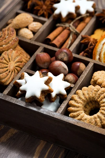 Деревянная коробка с рождественскими сладостями и специями на деревянном фоне — стоковое фото