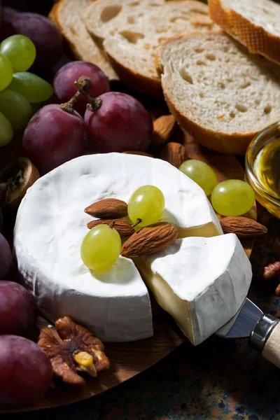 Queijo camembert, frutas e mel sobre um fundo escuro — Fotografia de Stock