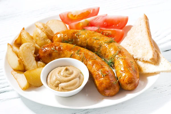 Fried sausages with potatoes and mustard on plate, closeup — Stock Photo, Image