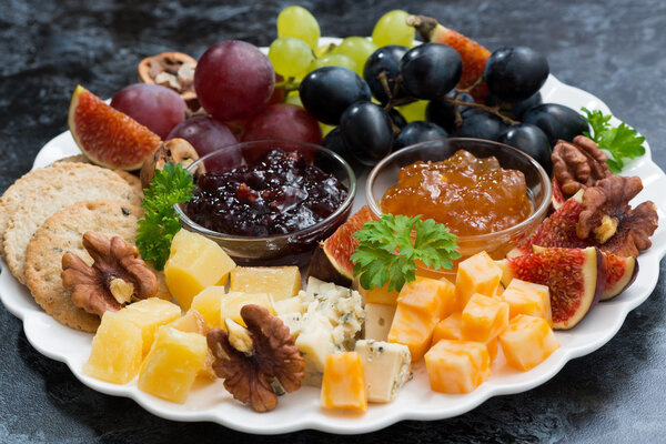 festive appetizers - cheeses, fruits and jams, closeup