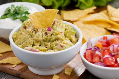 Guacamole sosu, domates salsa ve mısır cipsi bir ahşap tahta üzerinde