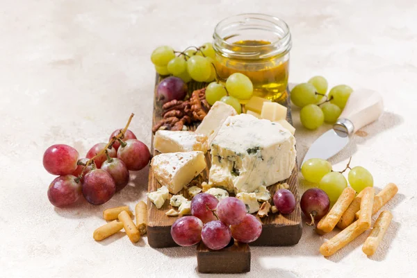 Cheeseboard, fruits and honey on the white fone — стоковое фото
