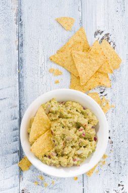 Baharatlı avokado sosu ve mısır cipsi Beyaz ahşap zemin üzerinde