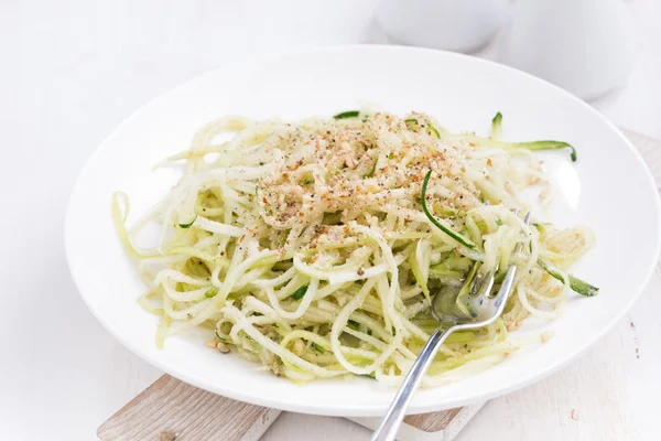 Vegetarian pasta with zucchini and nuts on white table — Stock Photo, Image