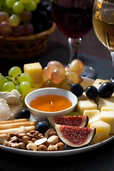 Plate with deli snacks and wine on a dark background, closeup — Stock Photo, Image