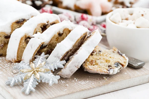 Vánoční Stollen na dřevěném prkénku a sladkosti, detail — Stock fotografie