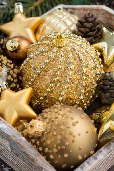 Golden Christmas decorations in a wooden box, vertical, closeup — Stock Photo, Image