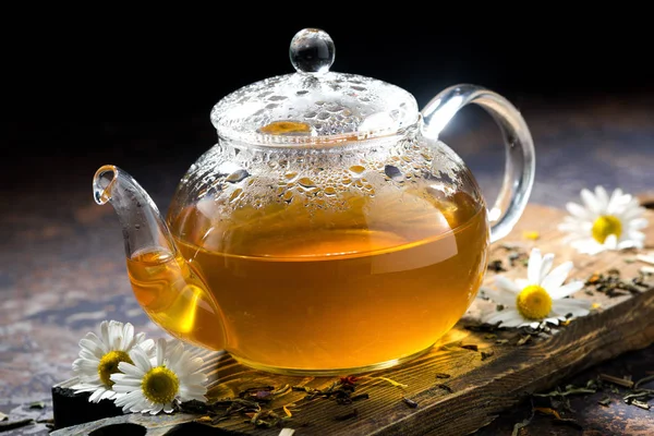 Glas-Teekanne mit Kamillentee auf dunklem Hintergrund, Nahaufnahme — Stockfoto