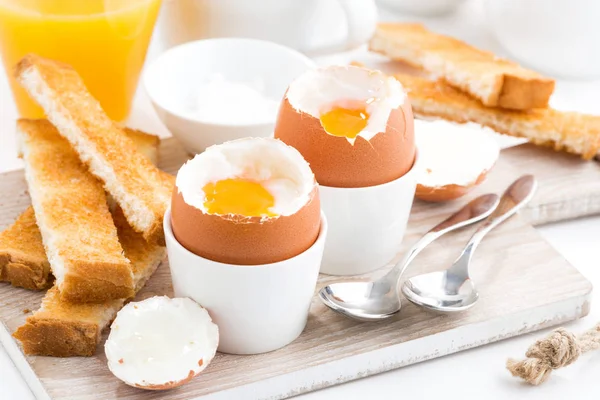 Вареные яйца и тосты на деревянной доске — стоковое фото