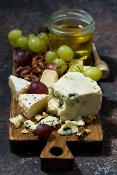 Plateau de fromages, fruits et miel sur fond sombre, vertical — Photo