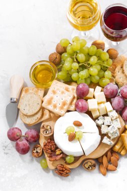 Camembert, üzüm, şarap ve aperatifler beyaz bir tabloda, üstten görünüm