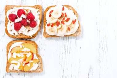 Beyaz ahşap masa üzerinde farklı Topingler ile tatlı ekmeği