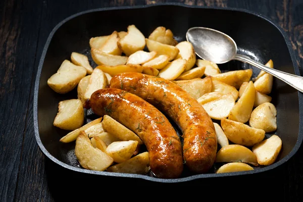Fried pork sausages with potatoes in frying pan, horizontal — Stock Photo, Image