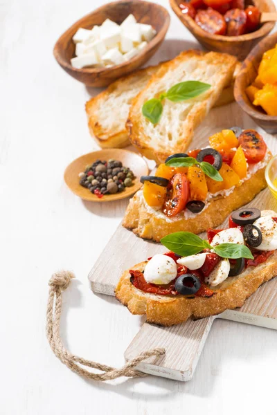 Bruschettas with tomatoes and mozzarella on wooden board — Free Stock Photo