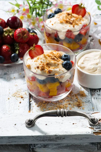 Свіжий фруктовий десерт з заварним кремом в окулярах на білому дерев'яному лотку — стокове фото