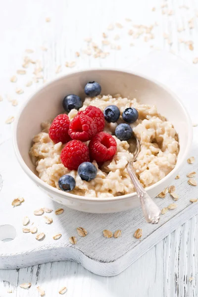 homemade oatmeal with berries on white wooden table, closeup