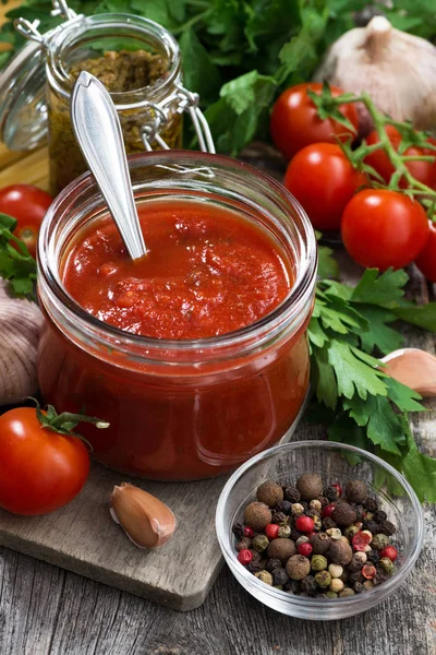 Salsa de tomate en un frasco de vidrio e ingredientes, vertical —  Fotos de Stock
