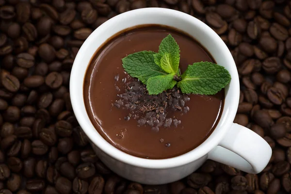 Чашка горячего мятного шоколада на фоне кофейных зерен — стоковое фото