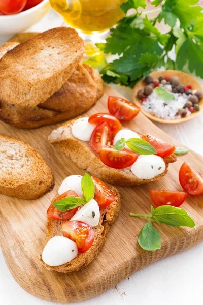 Toasts with mozzarella, basil and cherry tomatoes, top view — Stock Photo, Image