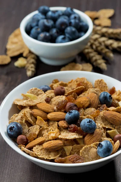 Cereal flakes with blueberries and nuts on a dark table — Stock Photo, Image