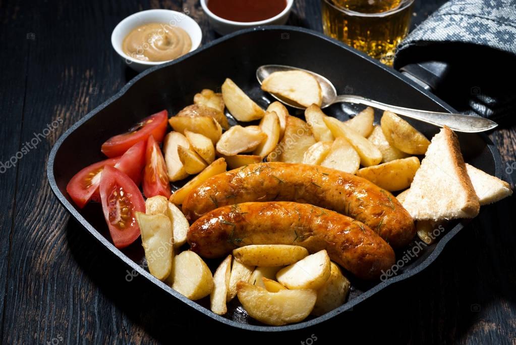 Fried pork sausages with potatoes in frying pan for lunch — Stock Photo