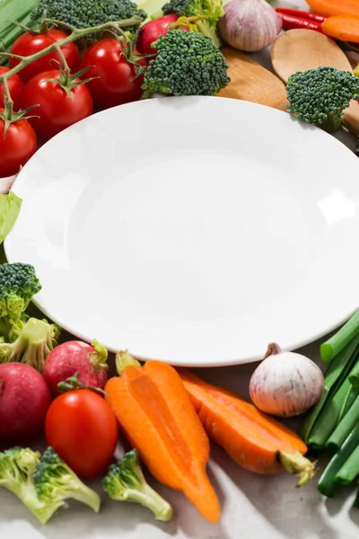 Background white plate and organic vegetables, vertical — Stock Photo, Image