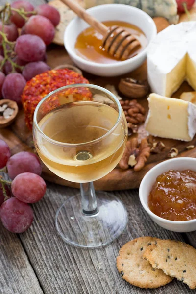 Copo de vinho branco frio e lanches em uma mesa de madeira, vertical — Fotografia de Stock