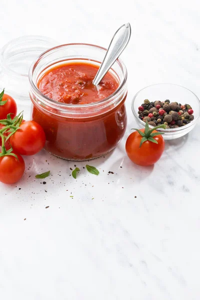 Molho de tomate em um frasco de vidro no fundo branco, vertical — Fotografia de Stock