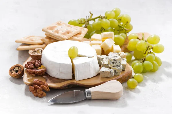 Camembert, виноград и крекеры на белом фоне, крупным планом — стоковое фото