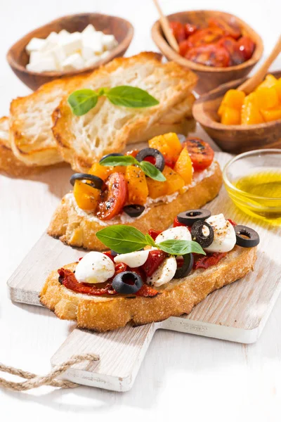 Bruschettas con tomates y mozzarella sobre tabla de madera —  Fotos de Stock