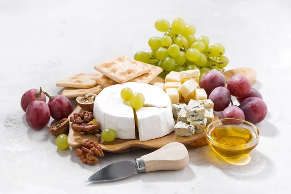 Camembert, uvas e bolachas em uma mesa branca — Fotografia de Stock