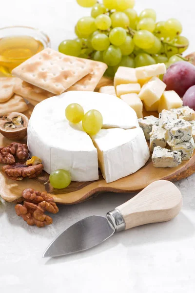 Camembert, grapes and crackers on a white table, vertical — Stock Photo, Image