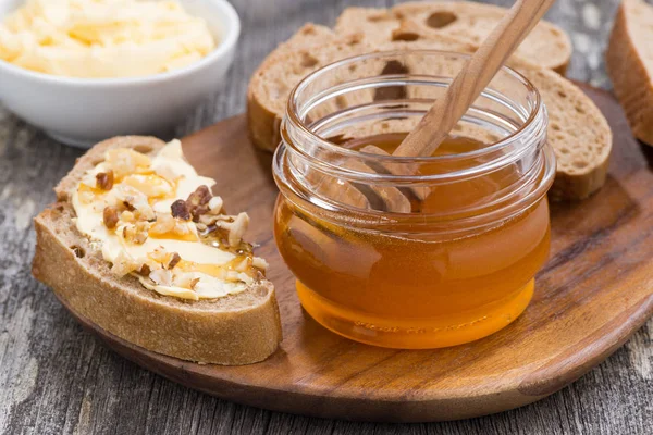 flavored honey, bread with butter and grape on wooden board