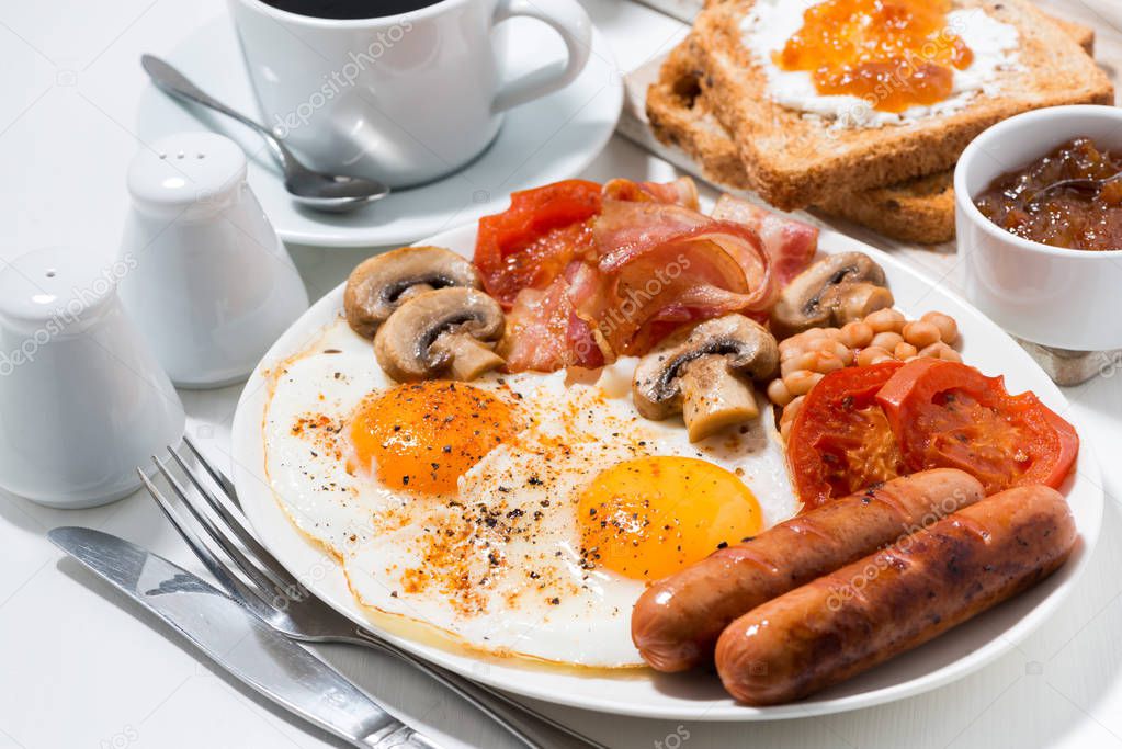 English breakfast of scrambled eggs with bacon, sausages