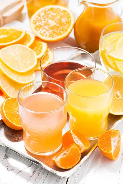 Fresh citrus juices on white table, vertical top view — Stock Photo, Image