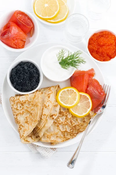 Traditionelle russische Crêpes mit Kaviar und gesalzenem Fisch, von oben — Stockfoto