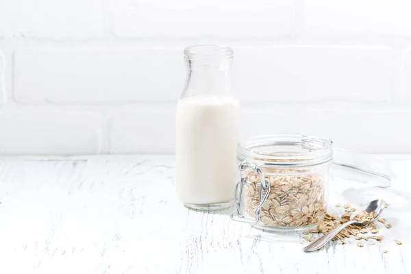 Copos de avena y una botella de leche sobre fondo blanco — Foto de Stock