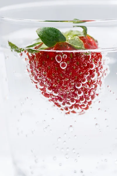 Kohlensäurehaltiges Wasser mit frischen Erdbeeren, vertikale Nahaufnahme — Stockfoto