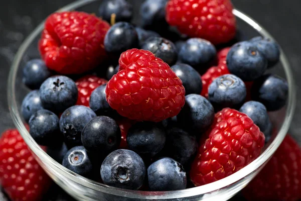 Frische Beeren in einer Glasschale auf dunklem Hintergrund, Nahaufnahme — Stockfoto